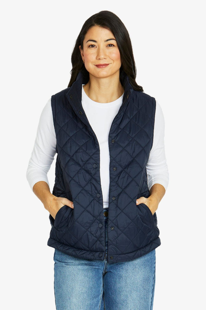 Woman wearing a navy quilted vest on a white background