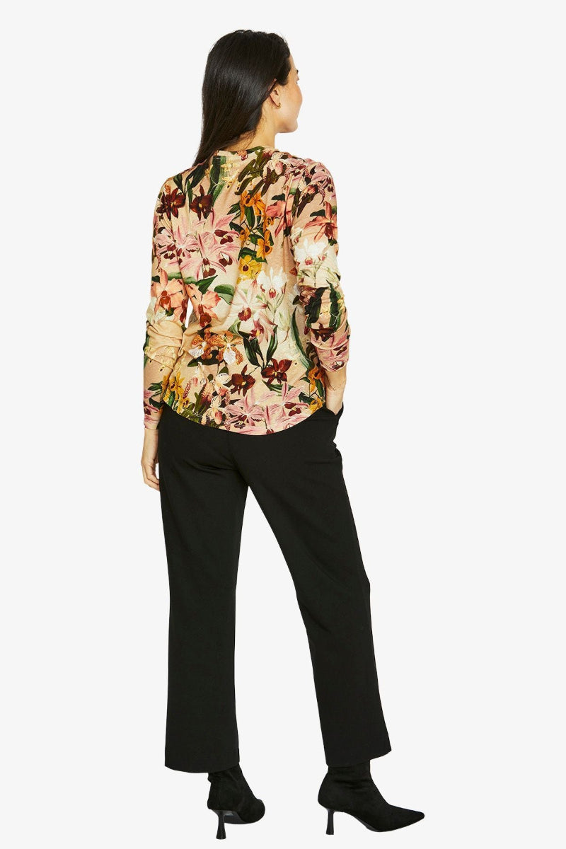 Woman wearing a floral blouse and black pants on a white background