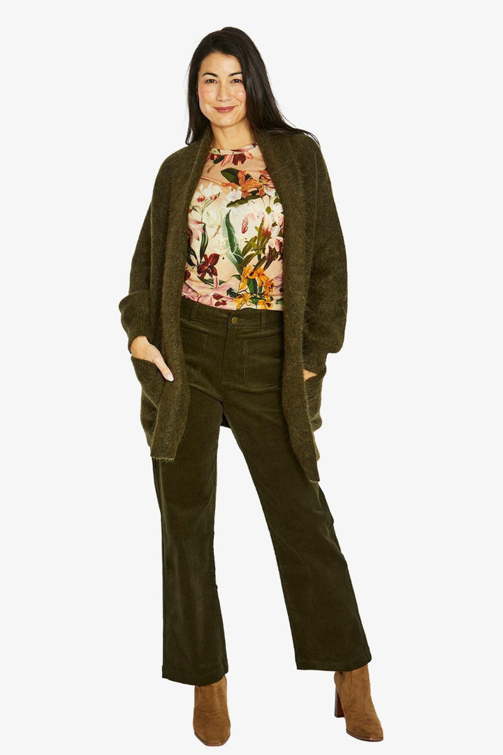 Woman wearing a floral top and green cardigan with matching pants on a white background