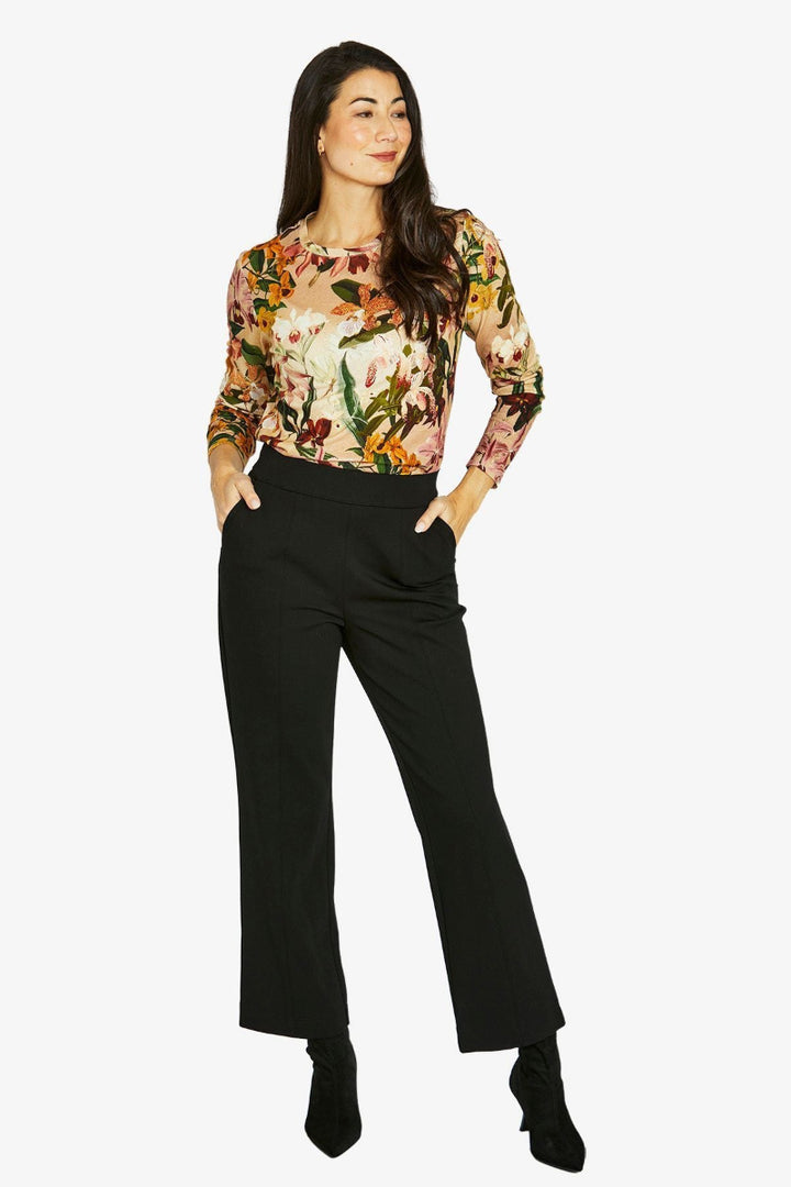 Woman wearing a floral blouse and black pants on a white background