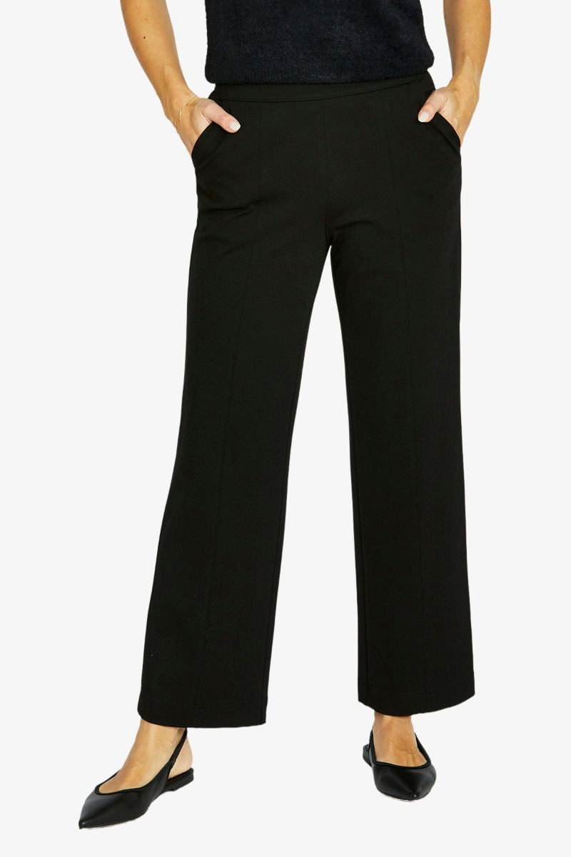 Person wearing black wide-leg pants on a white background