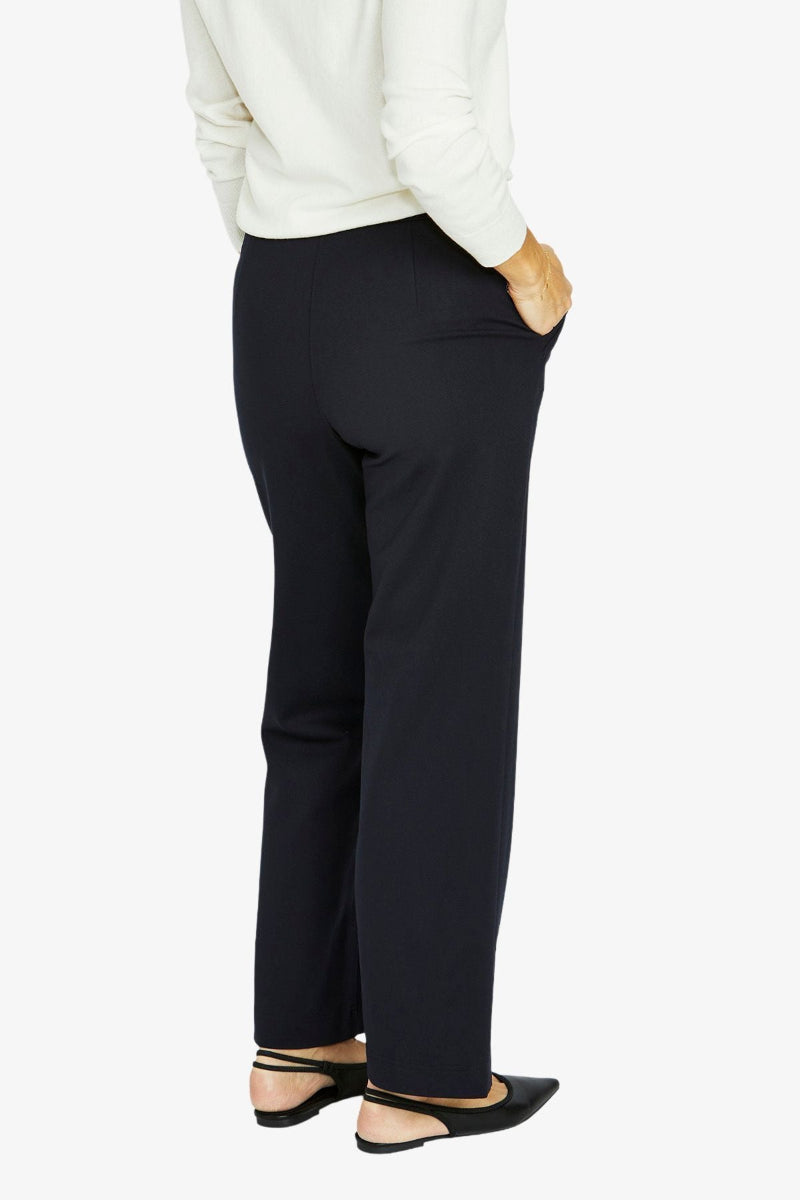 Person wearing black pants and a white top on a white background