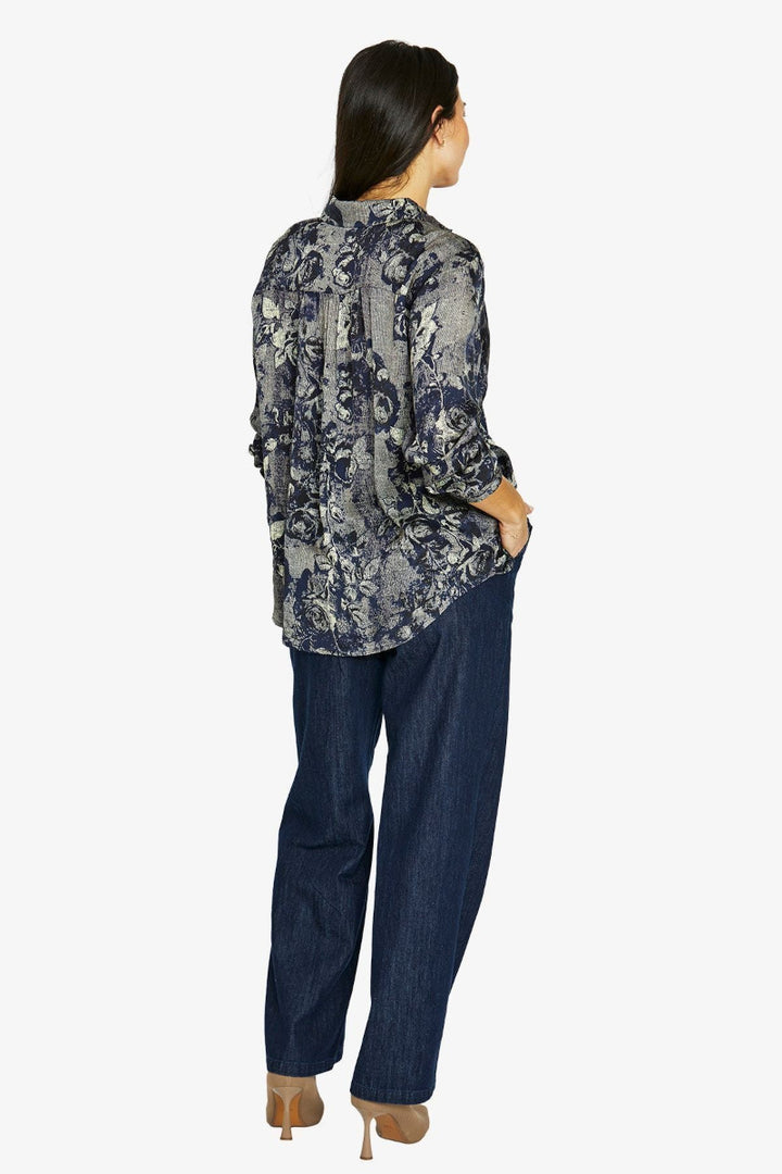 Woman wearing a patterned shirt and blue jeans on a white background