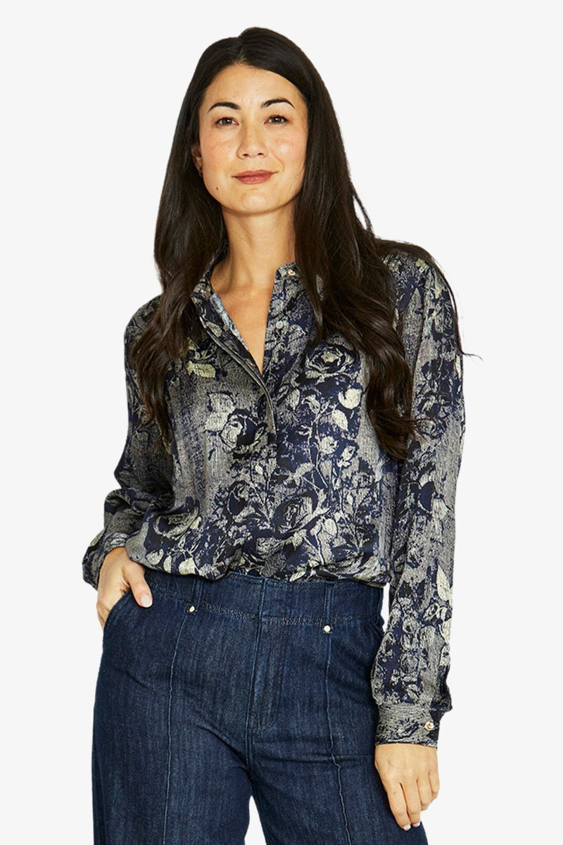 Woman wearing a floral blouse and dark jeans on a white background