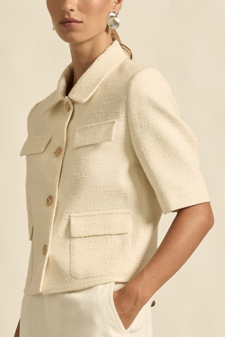 This side view of the Juncture Jacket in Alabaster showcases its sleek silhouette, structured shoulders, and clean lines for a modern, sophisticated style.
