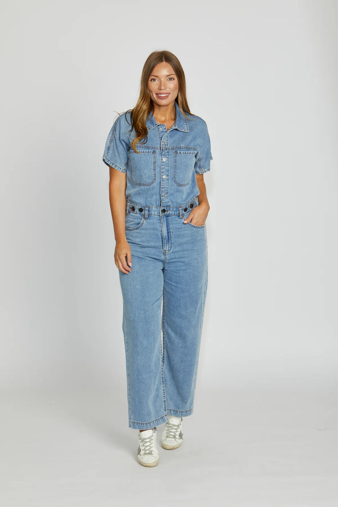 Woman wearing a denim jumpsuit on a white background