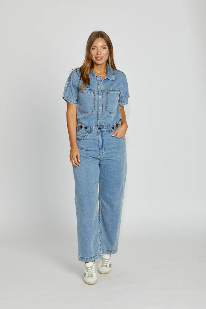 Woman wearing a denim jumpsuit on a white background