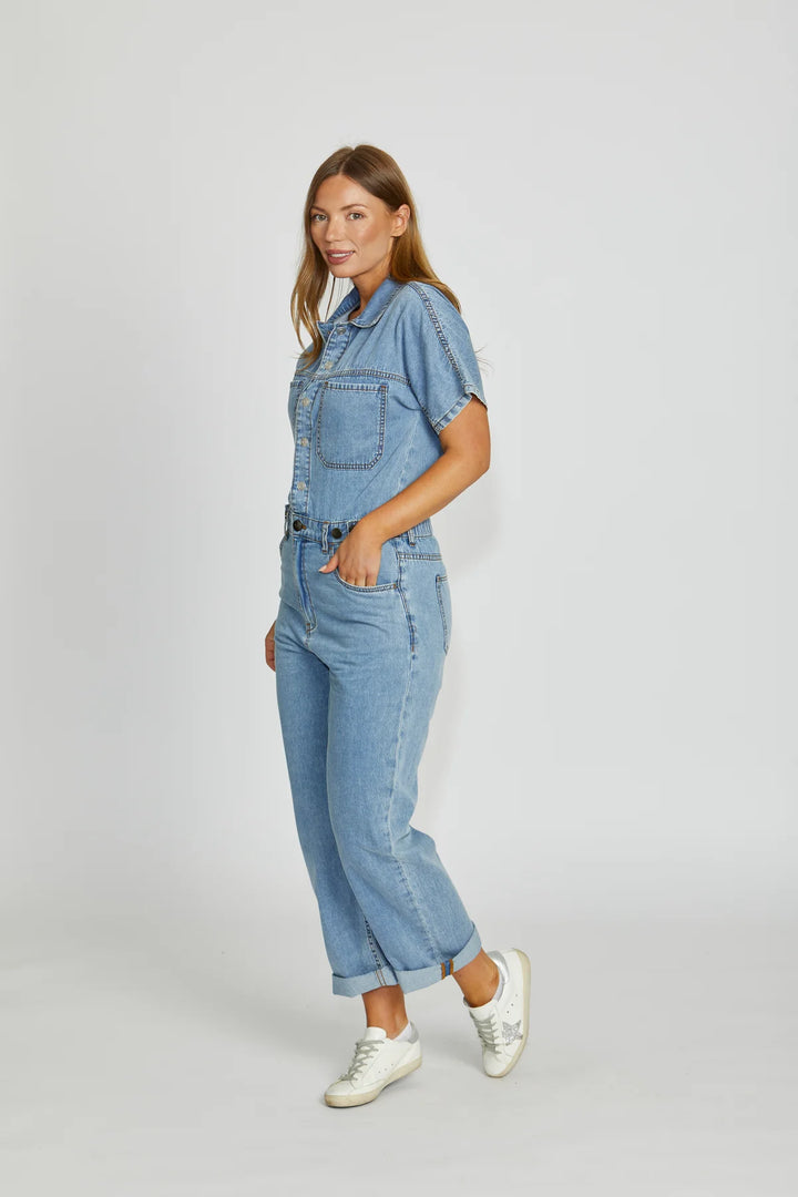 Woman wearing a denim jumpsuit on a white background