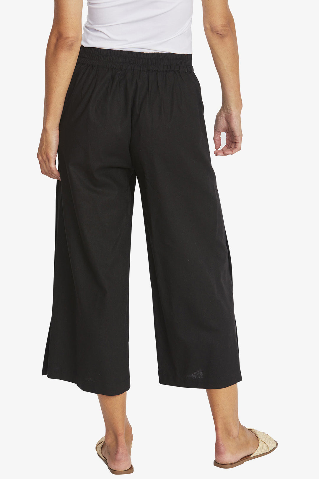 Person wearing black wide-leg pants on a white background