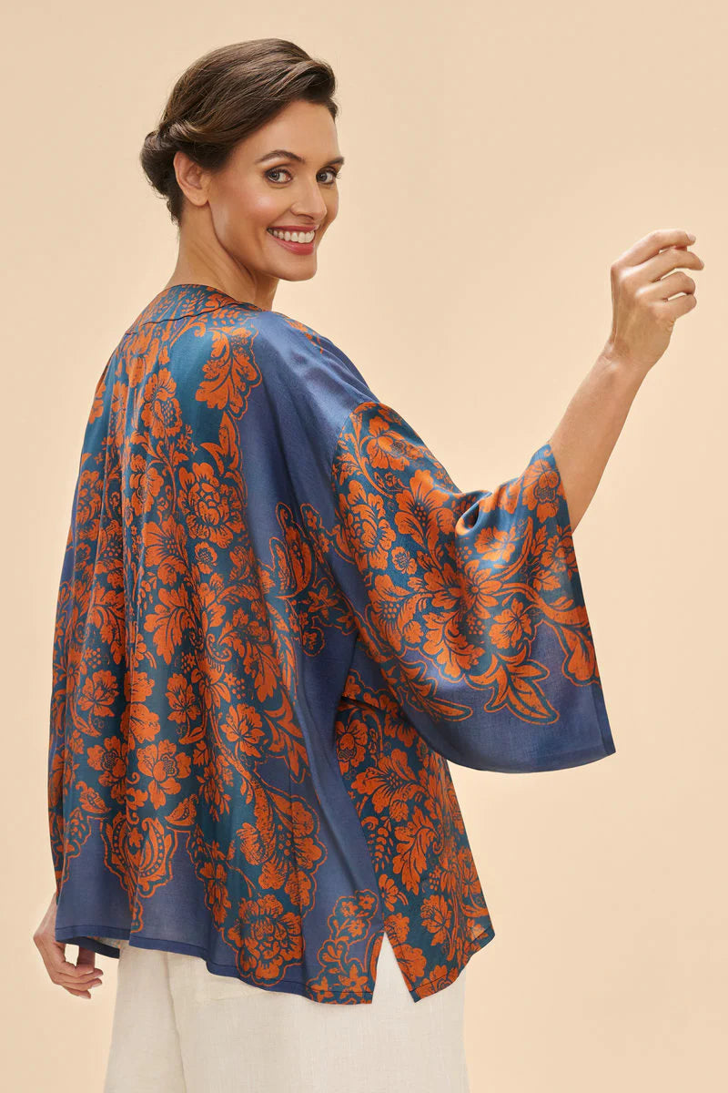 Woman wearing a blue and orange floral patterned blouse against a beige background