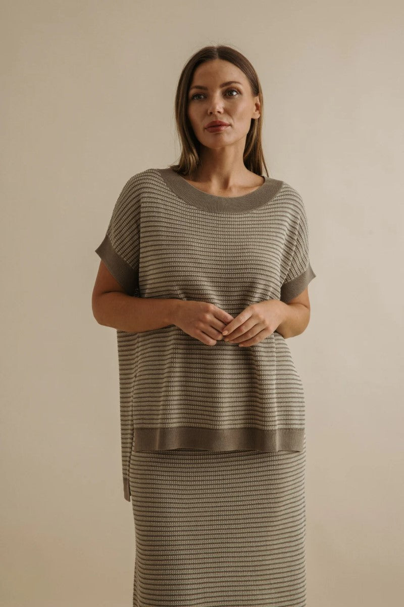 Woman wearing a matching top and skirt set against a plain background