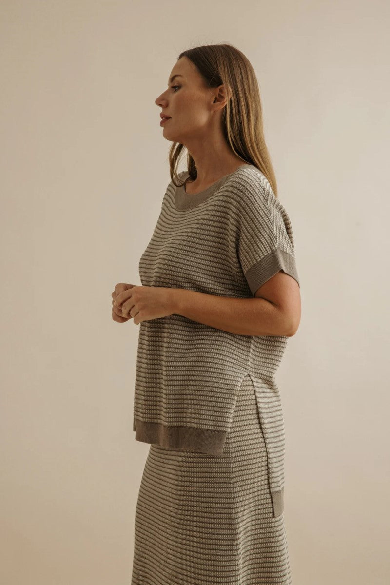 Woman wearing a matching striped outfit against a beige background
