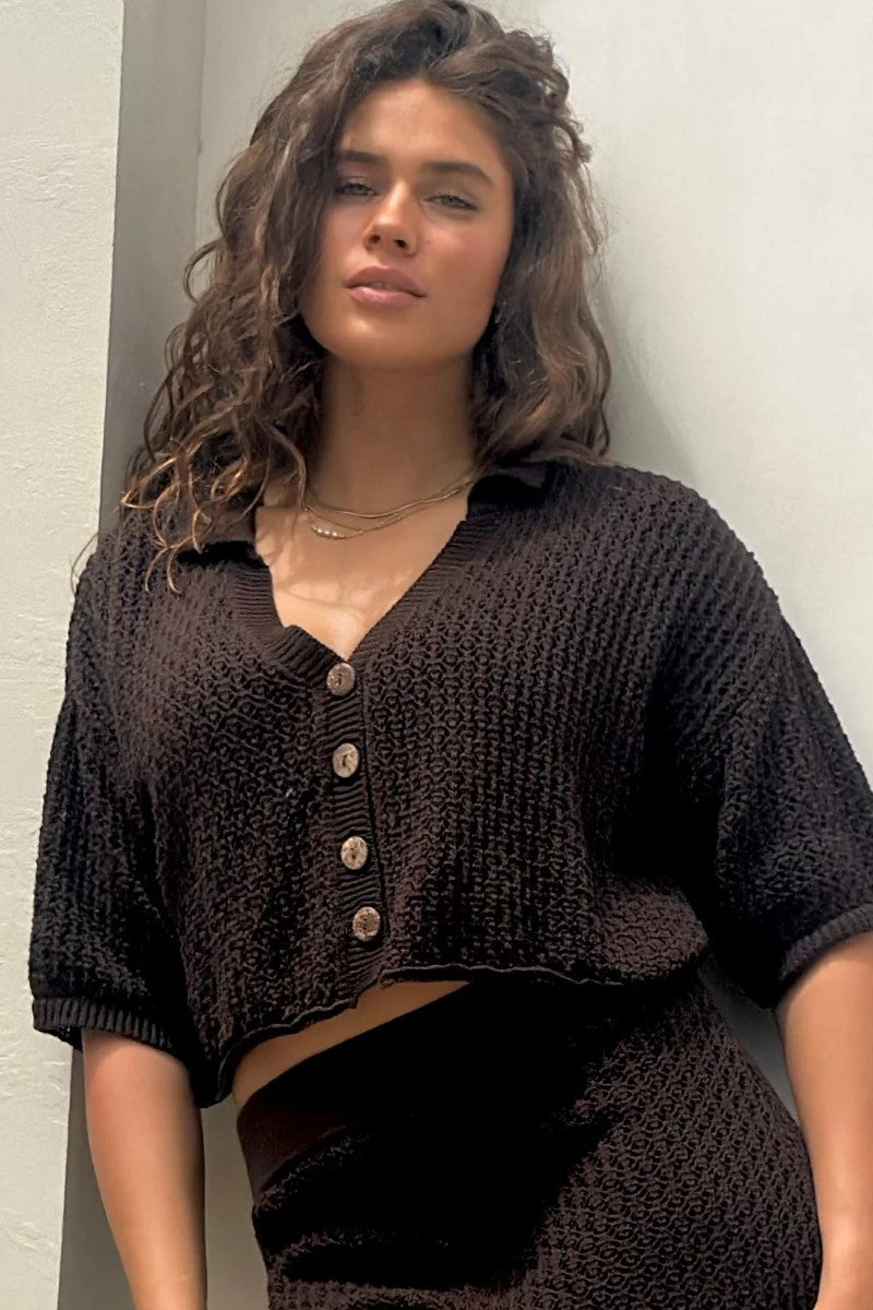 Woman wearing a dark brown knitted outfit against a light background