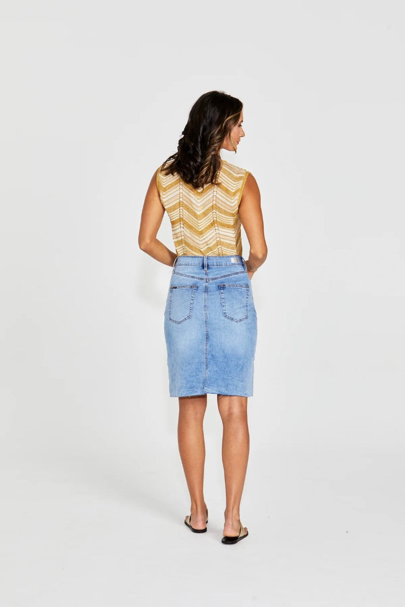 Woman wearing a yellow sleeveless top and denim skirt on a white background