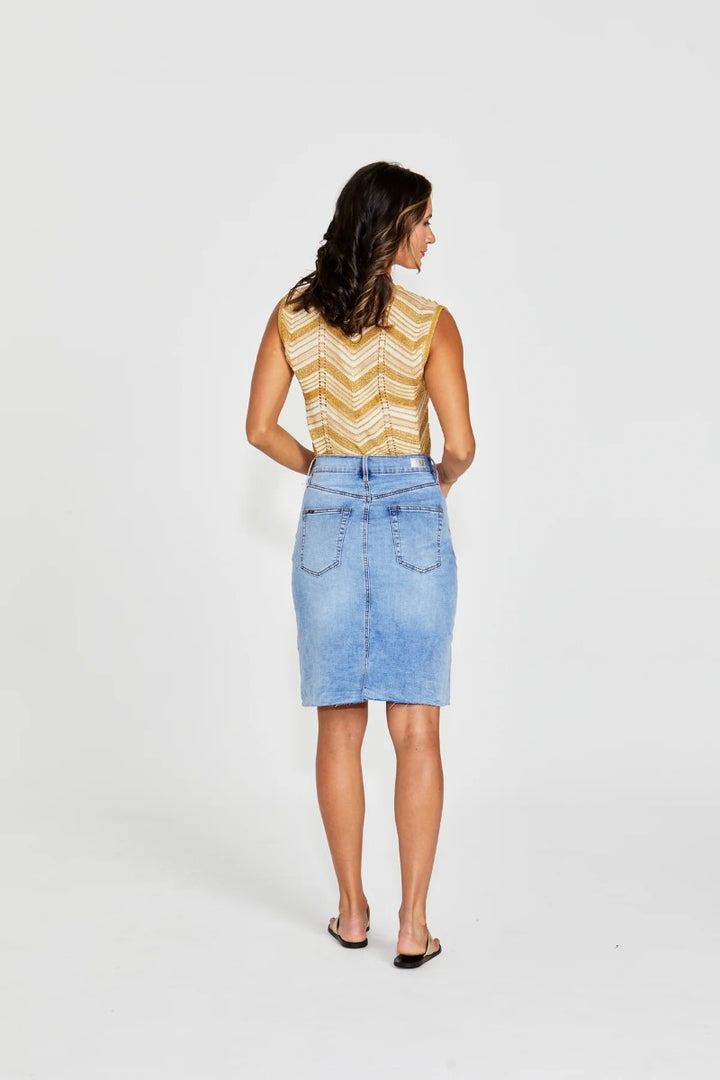 Woman wearing a yellow sleeveless top and denim skirt on a white background