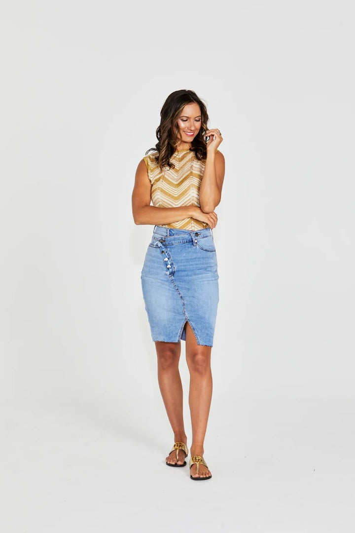 Woman wearing a yellow sleeveless top and denim skirt on a white background