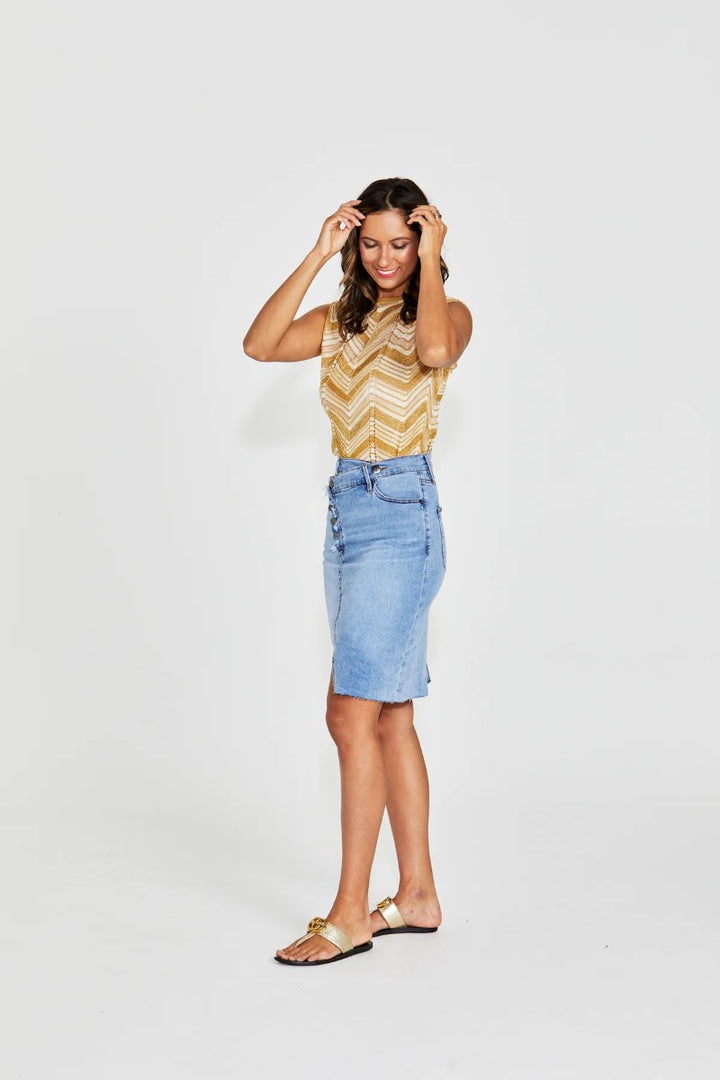 Woman wearing a yellow zigzag top and blue denim skirt on a white background