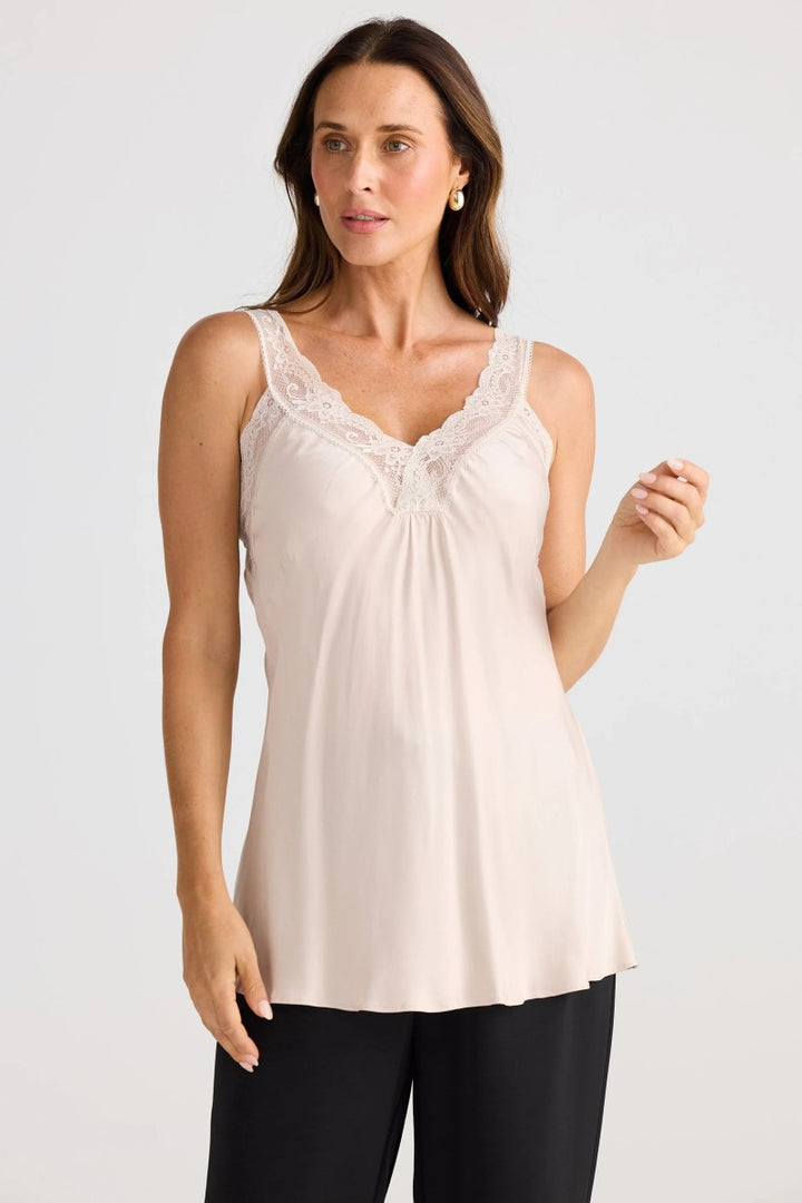 Woman wearing a beige sleeveless top with lace details on a white background