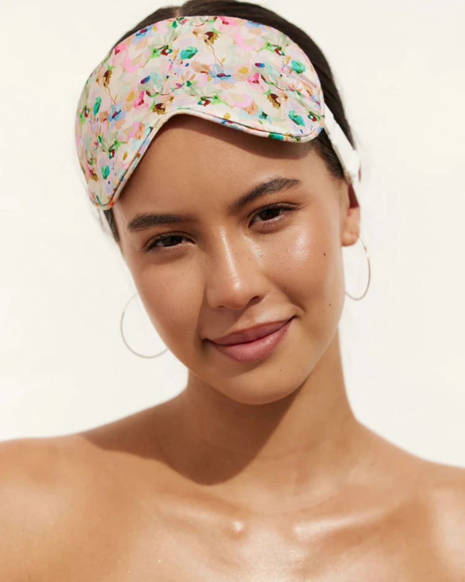Woman wearing a colorful sleep mask on a plain background