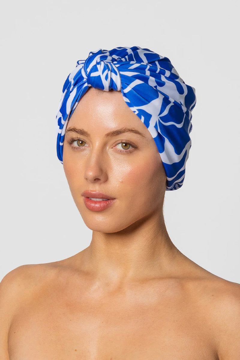 Woman wearing a blue and white patterned headscarf on a plain background