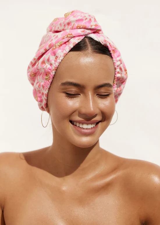 Woman wearing a pink floral towel on her head against a white background