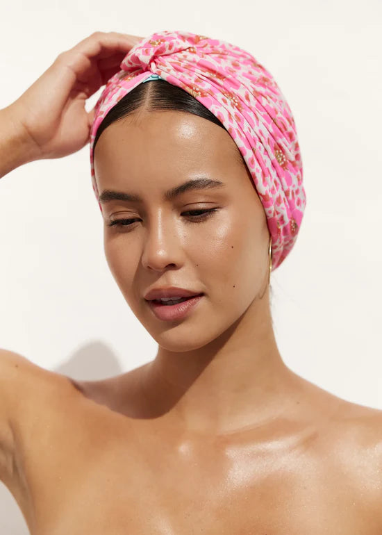 Woman wearing a pink patterned headscarf against a white background