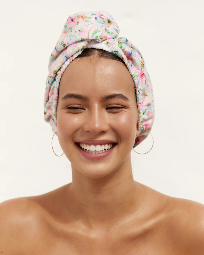 Woman wearing a floral towel on her head against a plain background