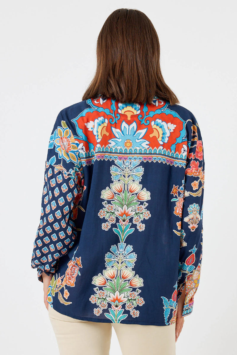 Woman wearing a colorful embroidered blouse with a white background