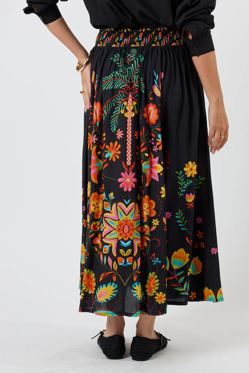 Person wearing a black skirt with colorful floral patterns on a white background