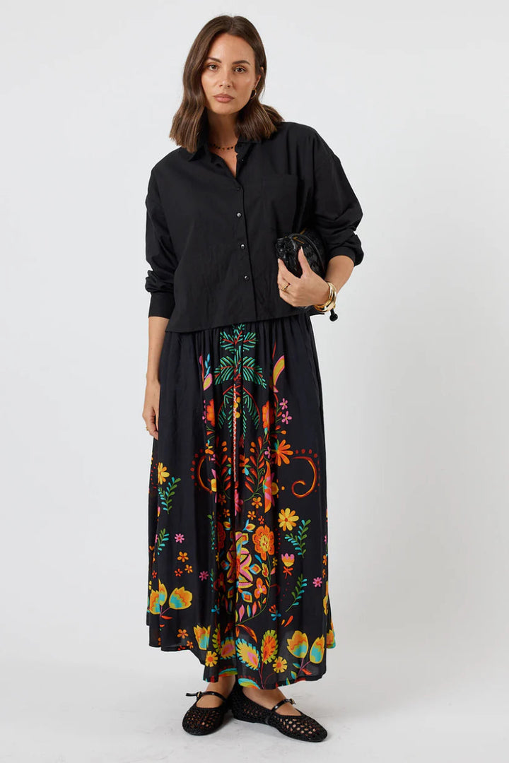 Woman wearing a black shirt and floral skirt on a white background