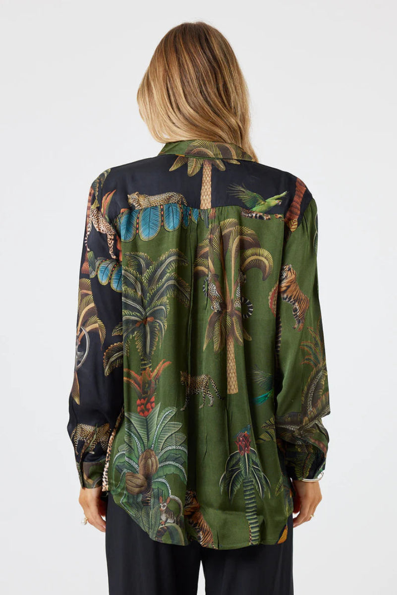 Woman wearing a long-sleeve shirt with a tropical pattern on a white background