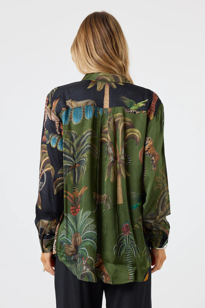 Woman wearing a long-sleeve shirt with a tropical pattern on a white background
