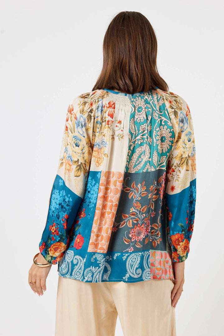Woman wearing a colorful patterned blouse on a white background