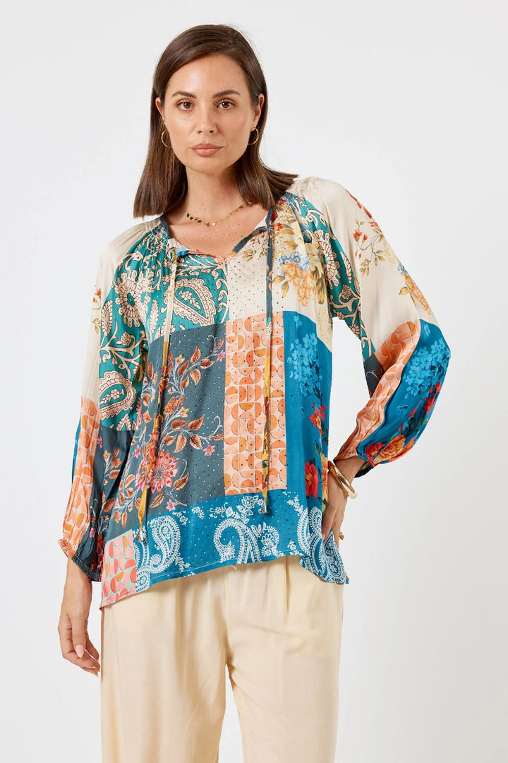 Woman wearing a colorful patterned blouse with a plain background