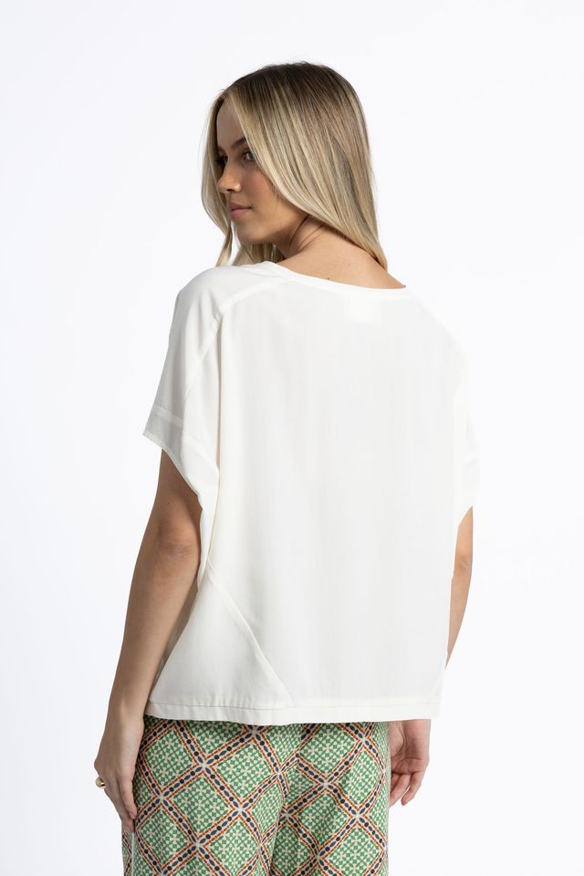 Woman wearing a white top and patterned pants on a white background