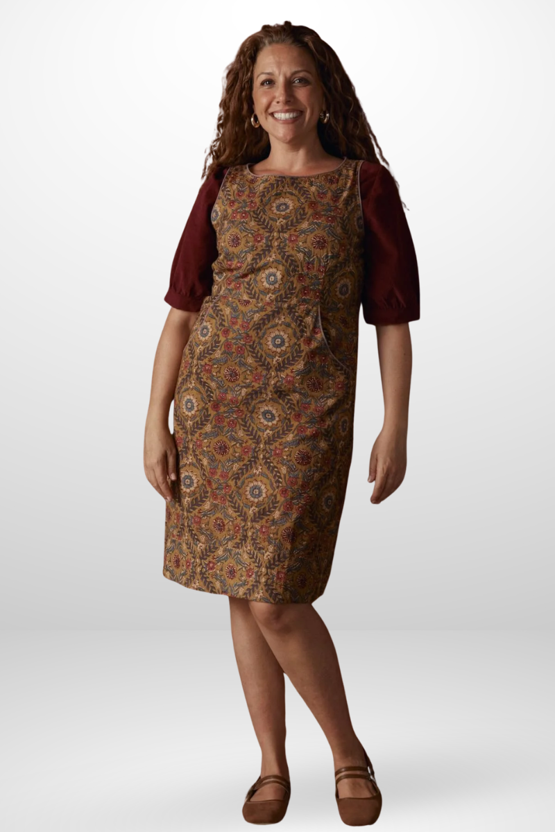 Woman wearing a patterned dress with a burgundy cardigan on a white background