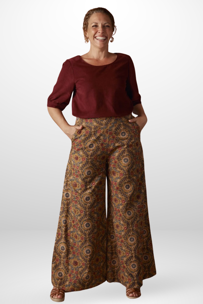 Woman wearing a burgundy top and patterned pants on a white background
