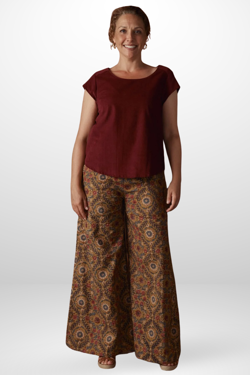 Woman wearing a burgundy top and patterned pants on a white background