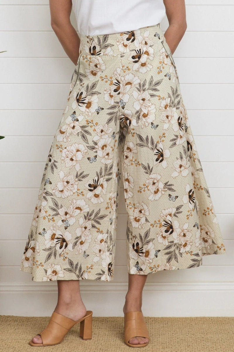 Person wearing floral wide-leg pants against a white wooden panel background