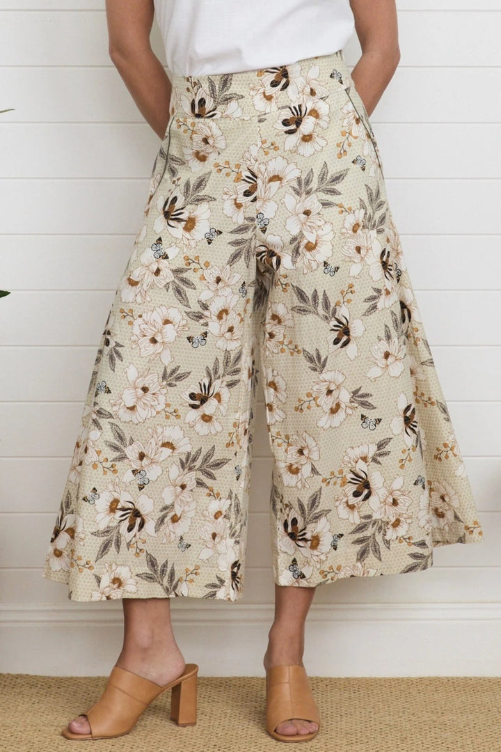 Person wearing floral wide-leg pants against a white wooden panel background