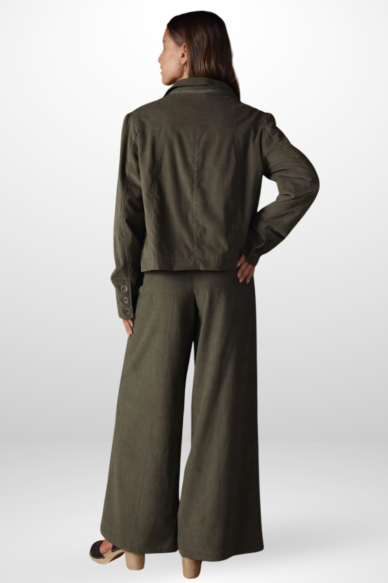 Person wearing a green jacket and wide-leg pants on a white background