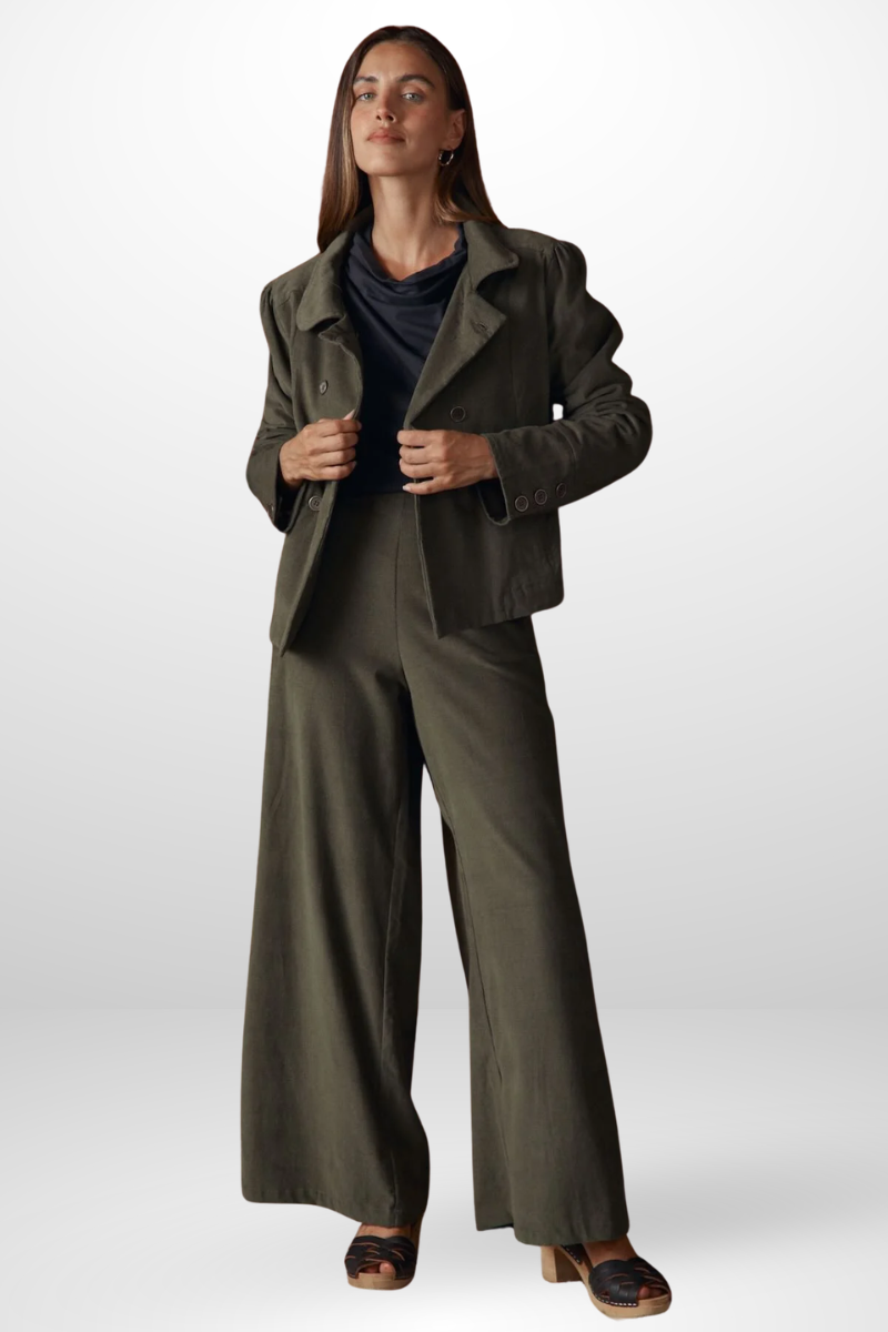 Woman wearing a green coat and wide-leg pants on a white background