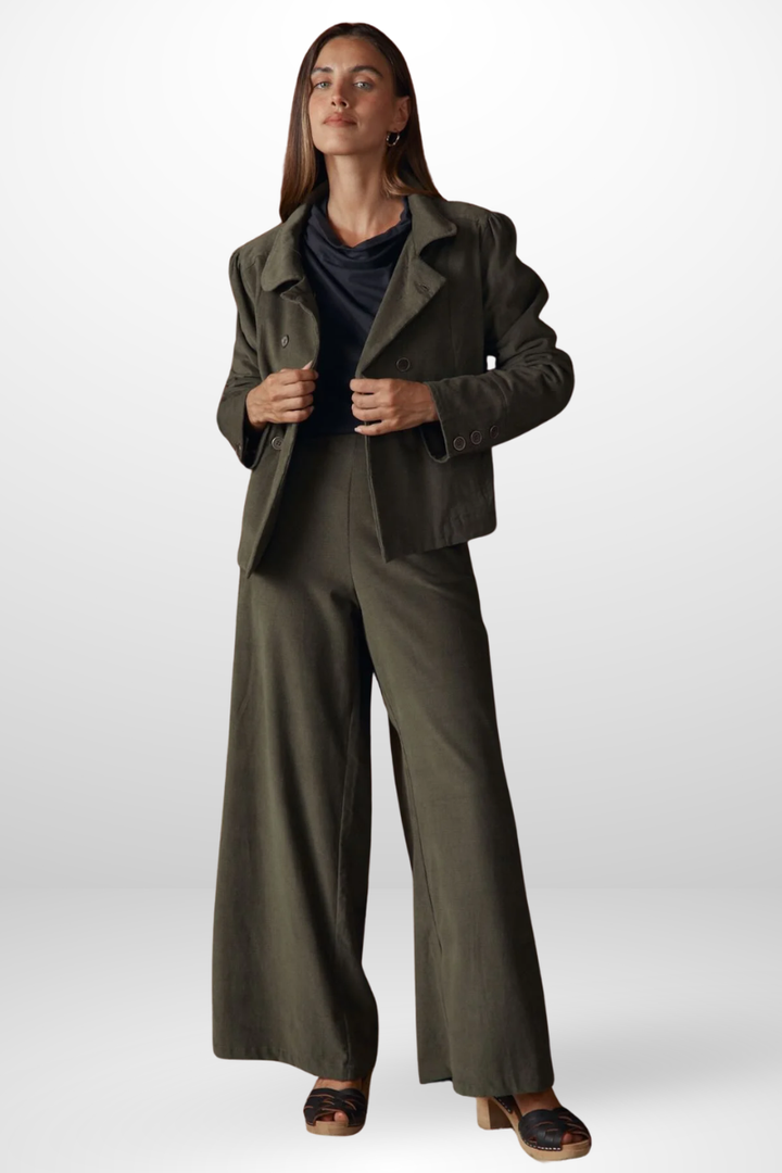 Woman wearing a green coat and wide-leg pants on a white background