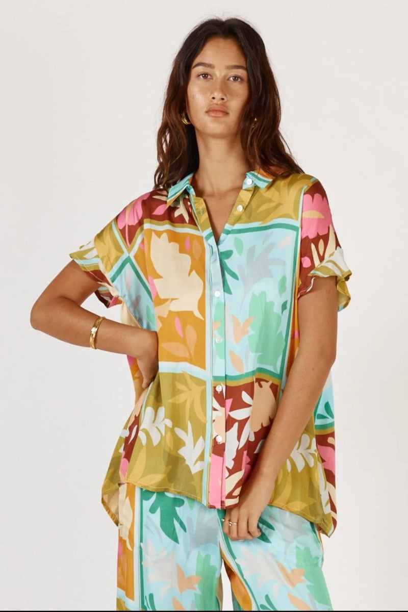 Woman wearing a colorful patterned shirt and pants on a white background