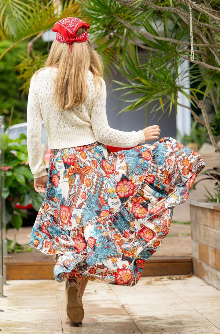 Back view of woman wearing frill maxi skirt and cream cardigan with red bandana.