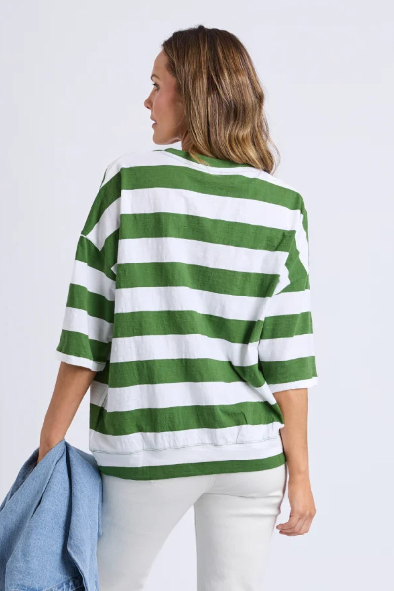 Woman wearing a green and white striped sweater against a plain background