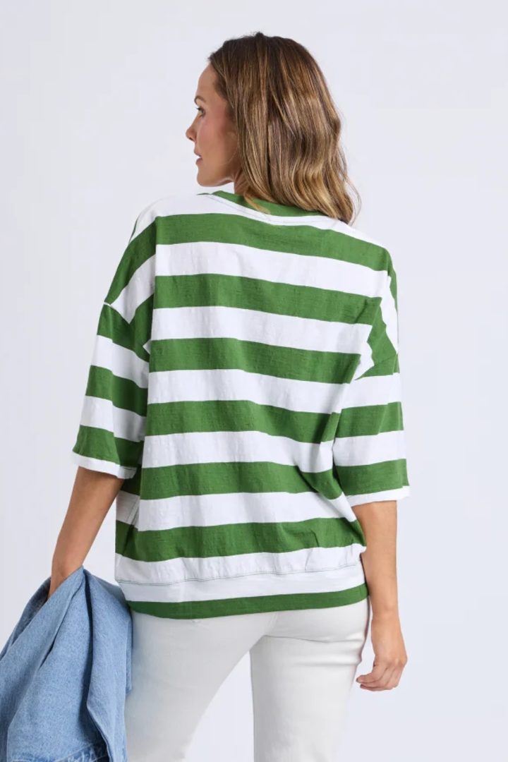 Woman wearing a green and white striped sweater against a plain background