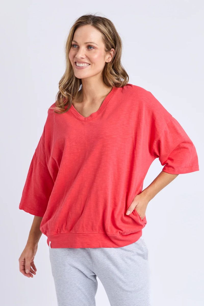 Woman wearing a red oversized shirt and gray pants on a white background