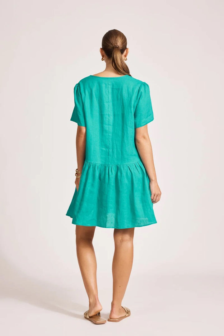 Woman wearing a teal dress on a plain background