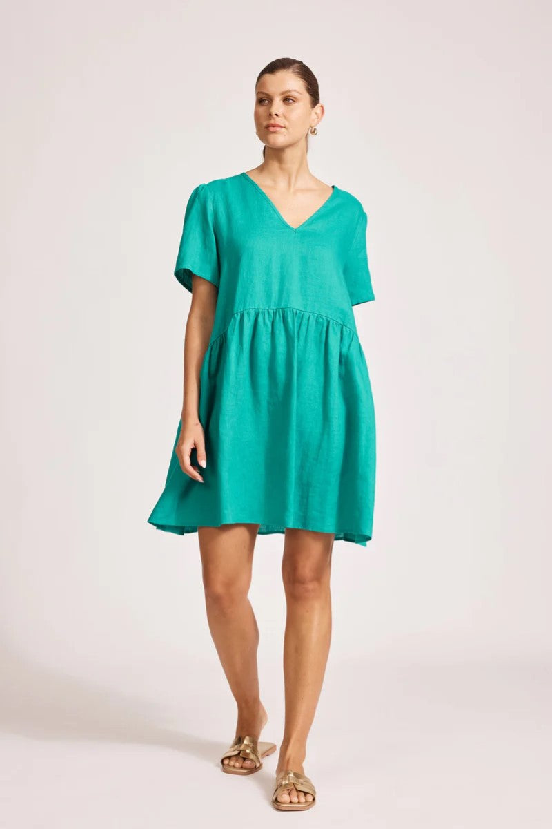Woman wearing a teal dress on a plain background